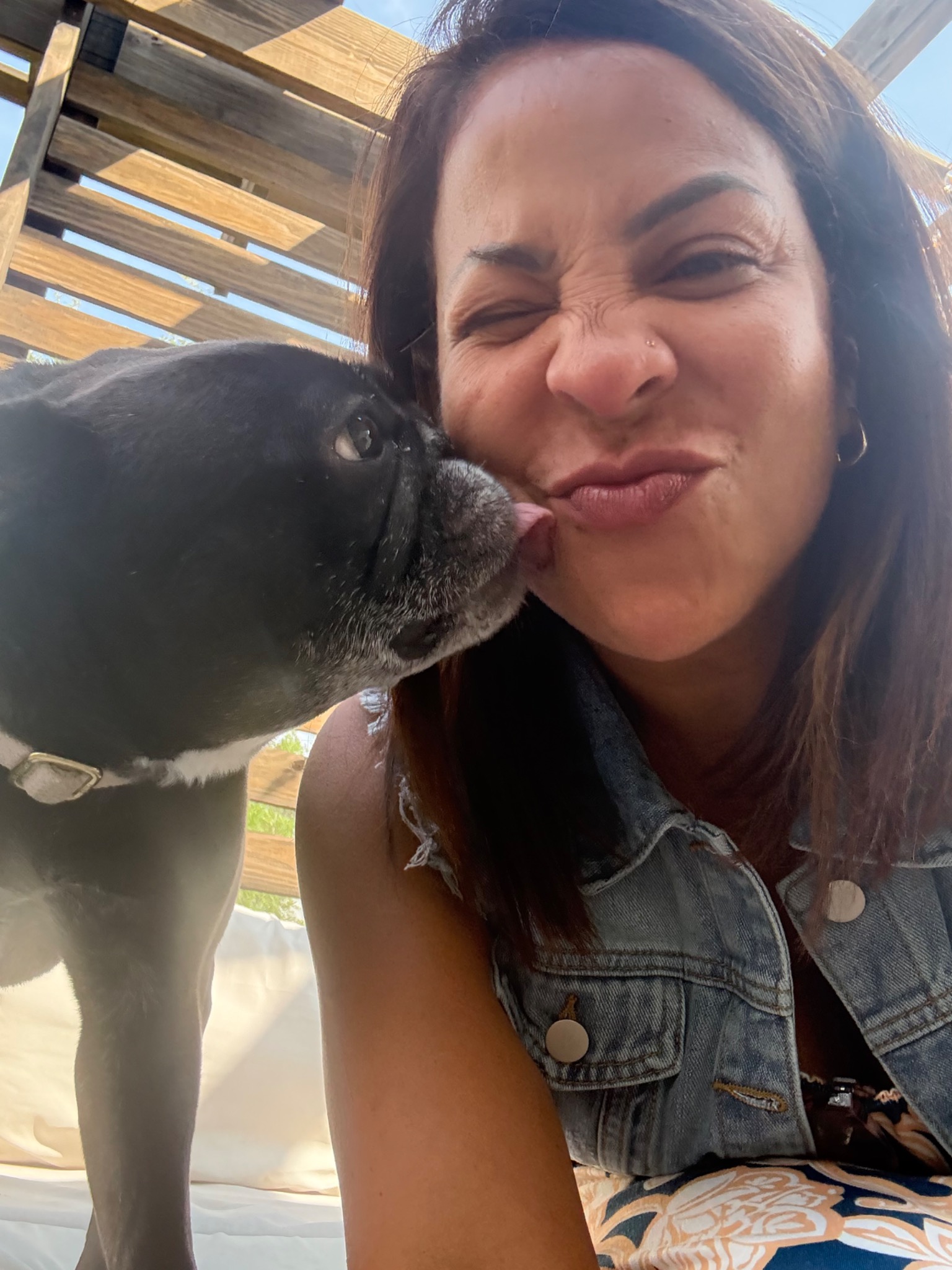 A black dog giving Neida a kiss